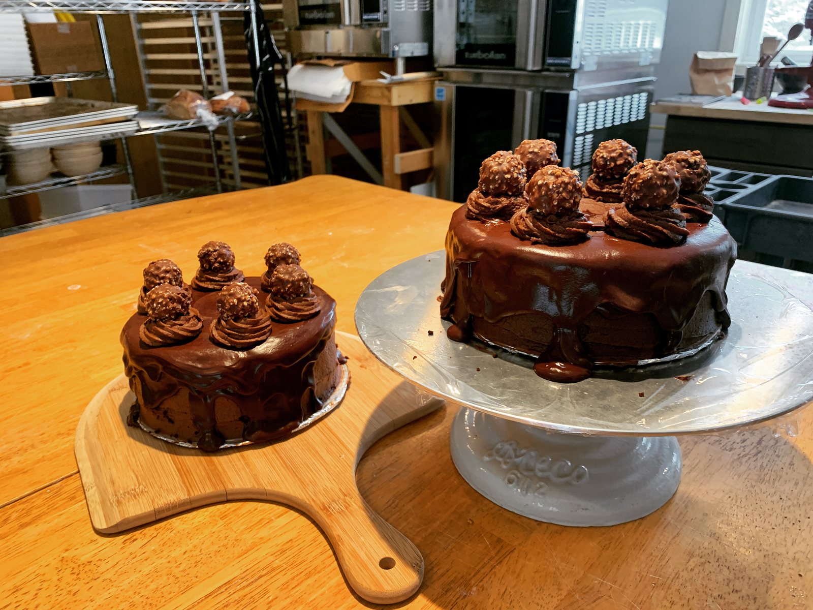 Two chocolate ganache cakes topped with truffles on wooden stands