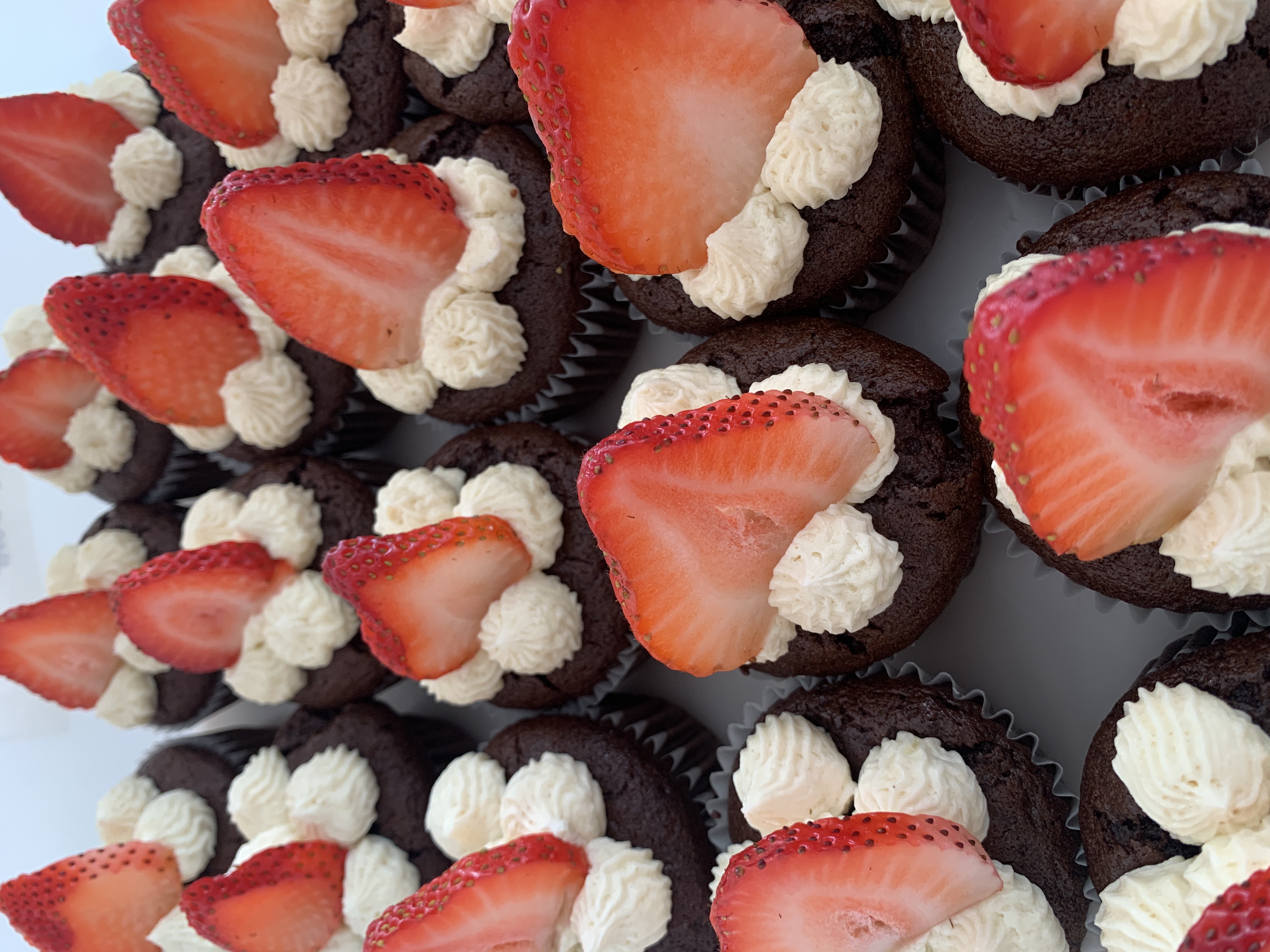 Chocolate cupcakes with swirled vanilla frosting and fresh strawberries