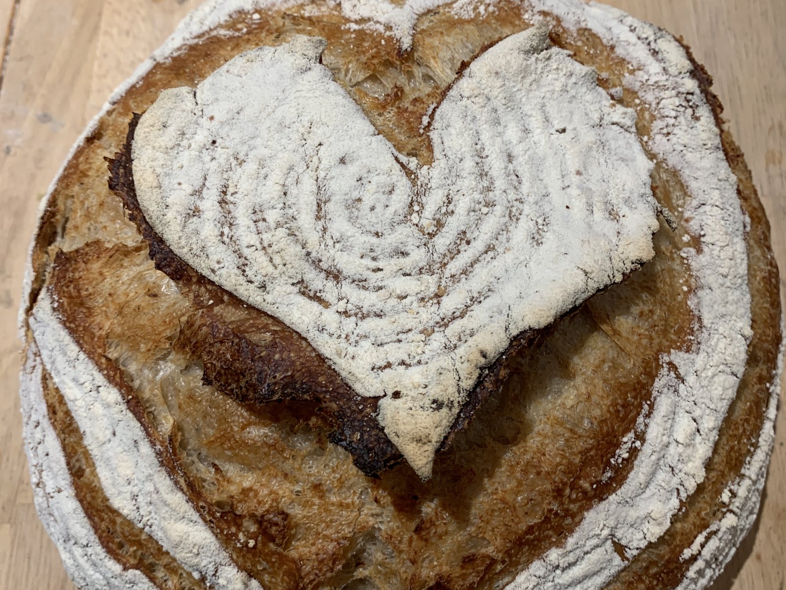 A round sourdough loaf scored with a heart pattern